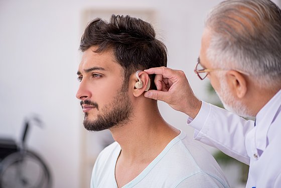 HNO-Arzt passt jungem Mann en Hörgerät an