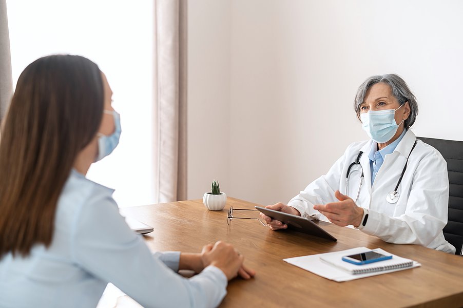 Ärztin mit Laptop im Gespräch mit einer Patientin