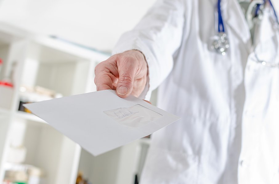 Arzt reicht einen Briefumschlag an einen Patienten