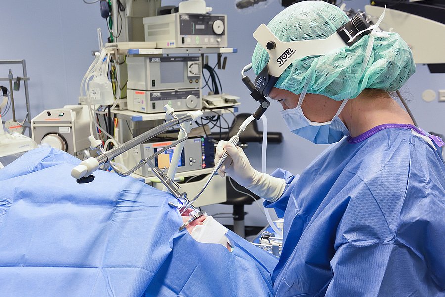 Ärztin operiert durch den geöffneten Mund eines abgedeckten Patienten